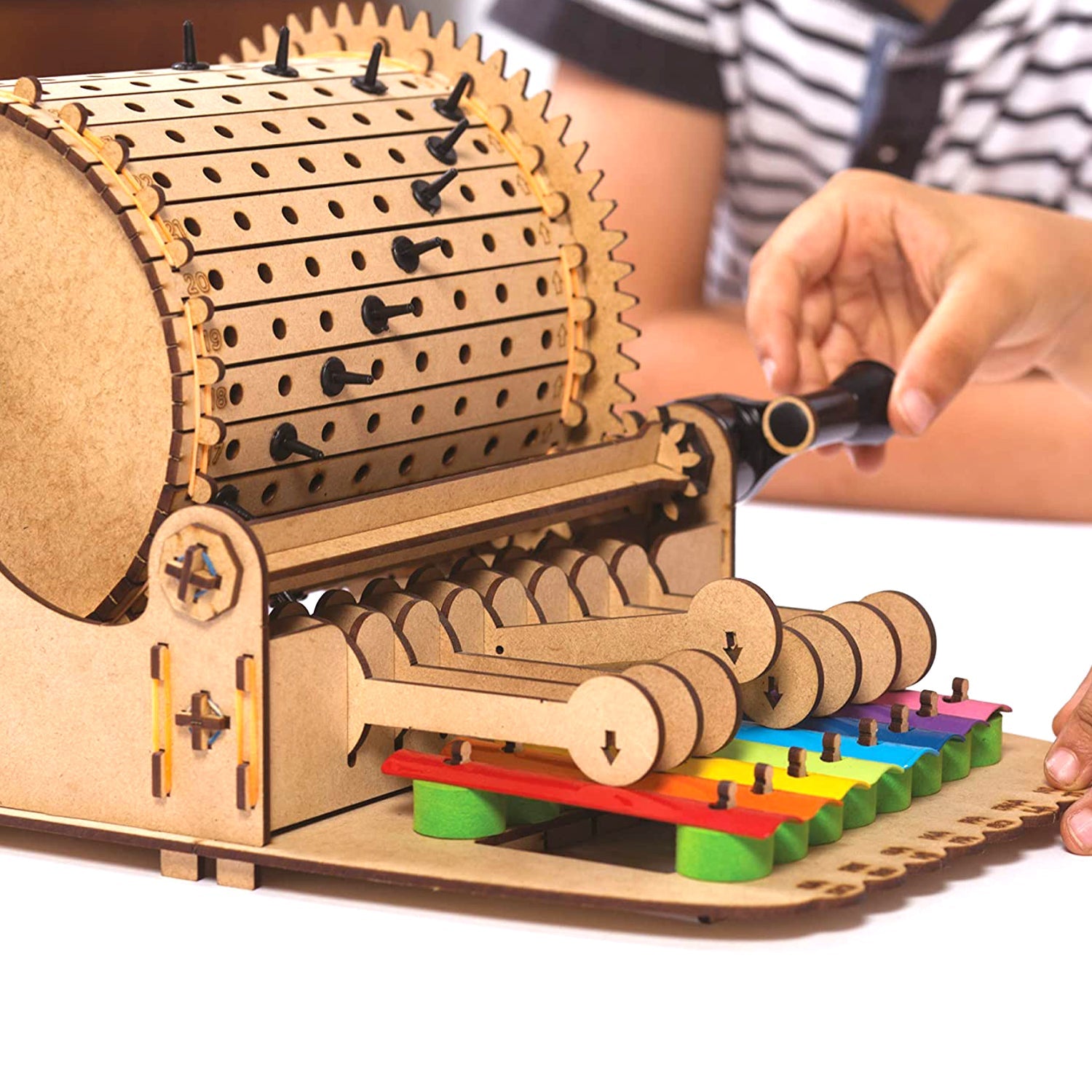 Wooden mechanical model with colorful components, being assembled by a person.